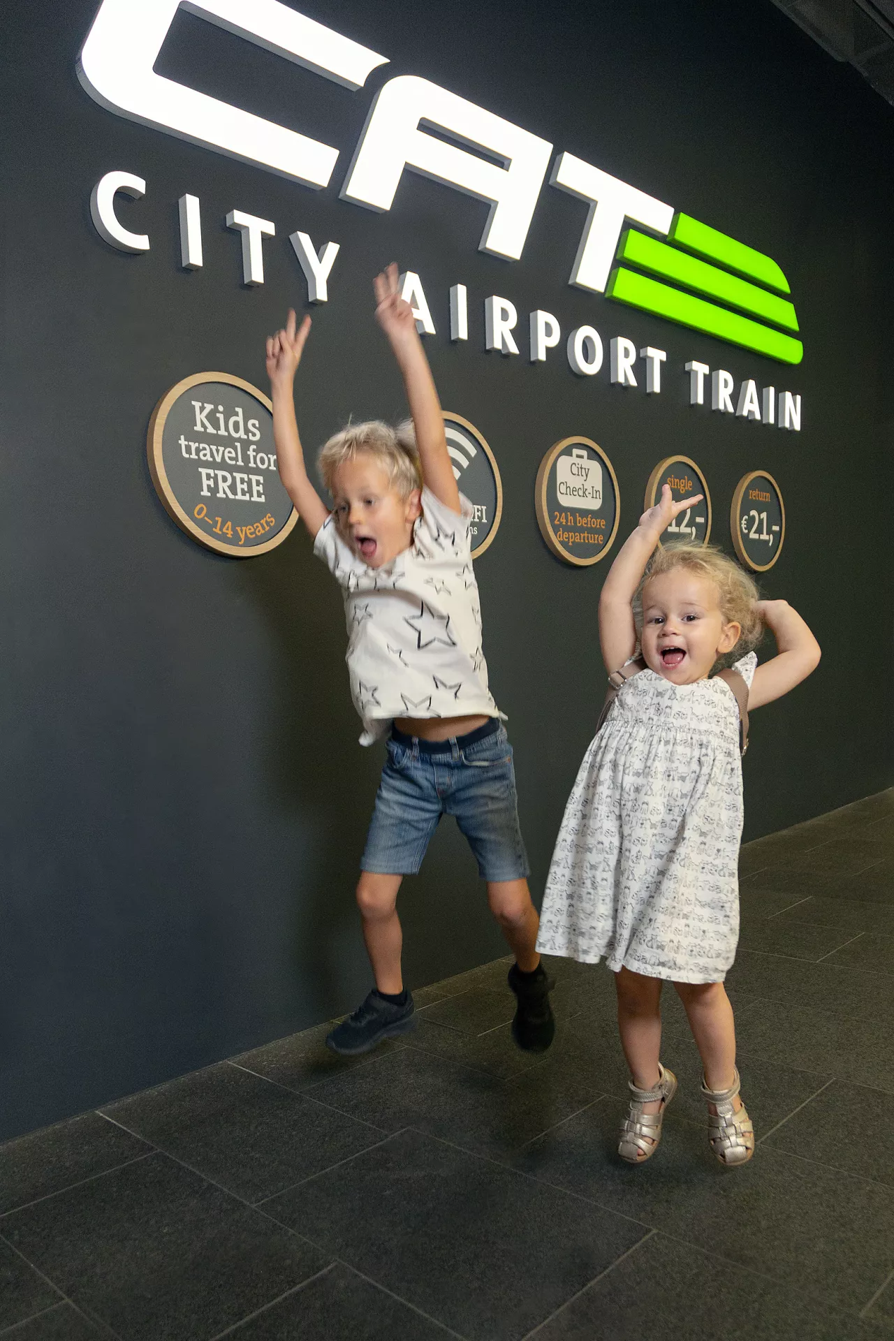 Children jumping in front of the City Airport Train logo in Wien Mitte
